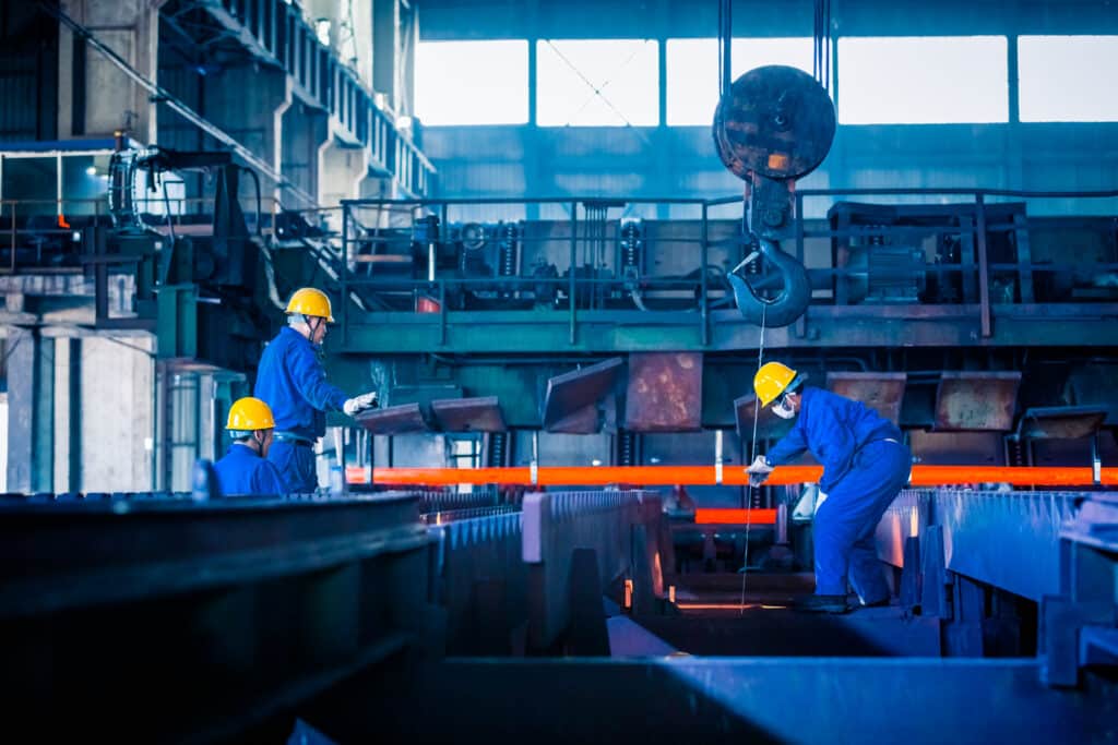 dois homens soldam uma coluna de ferro em uma indústria